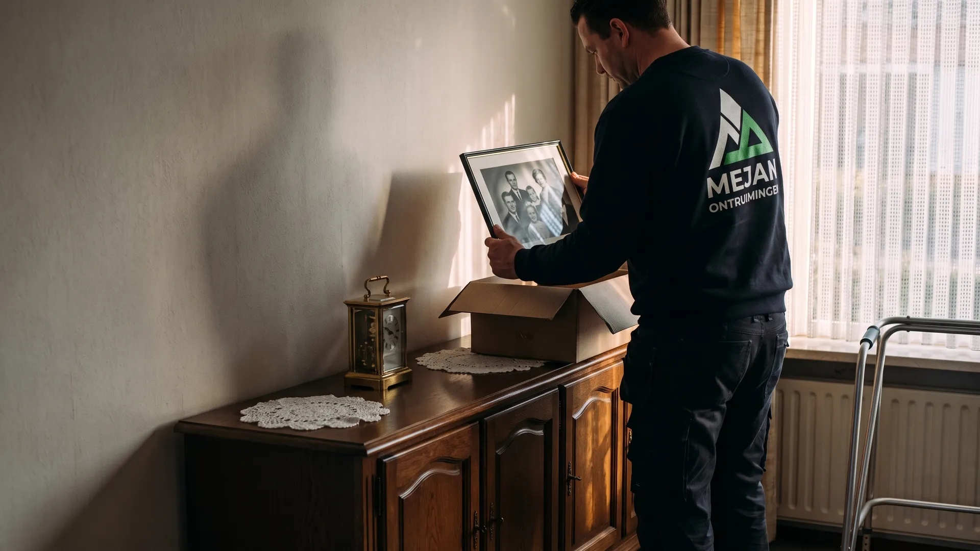 Medewerker legt een ingelijste familiefoto voorzichtig in een doos op het dressoir