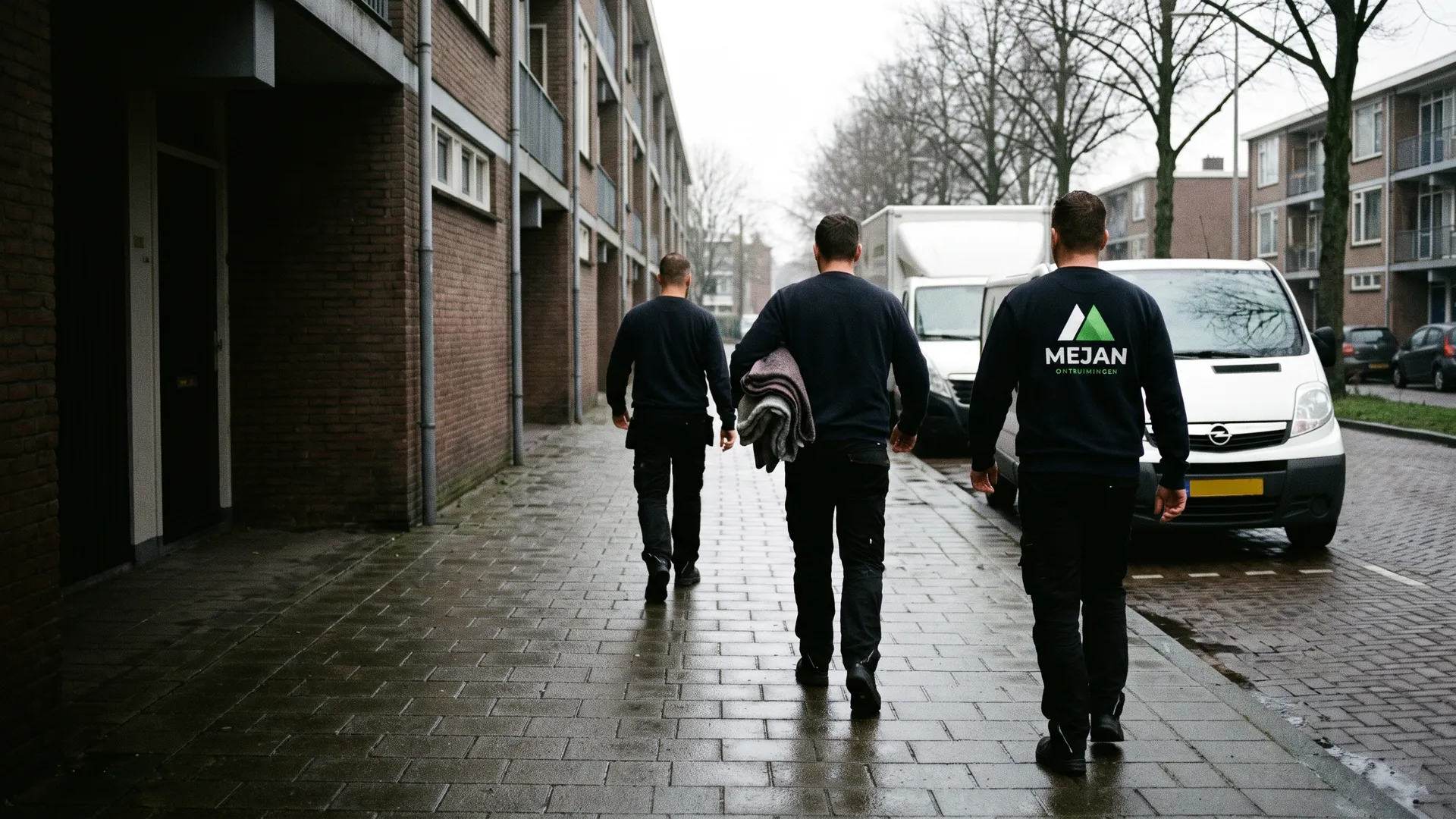 Drie medewerkers van Mejan lopen met het ruglogo in beeld naar de bus