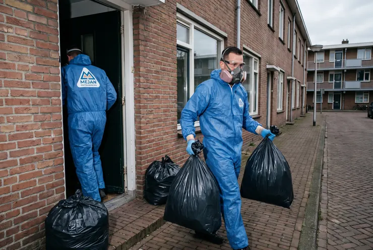 Medewerker in beschermende kleding aan het werk in een vervuilde woning